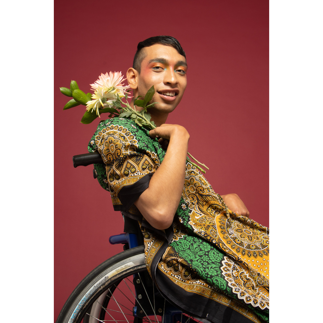 southeast asian man wearing eye makeup and sitting in a wheelchair 